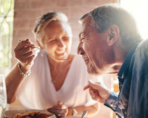 Senior couple smiling while enjoying a meal together