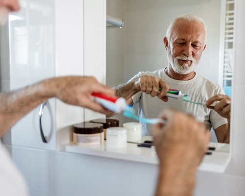 Senior man putting toothpaste on toothbrush