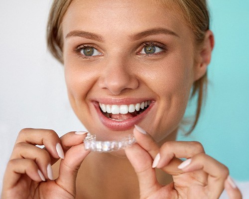 Smiling patient holding teeth whitening tray
