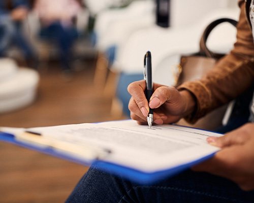 A dental patient filling out a dental insurance form in a waiting room