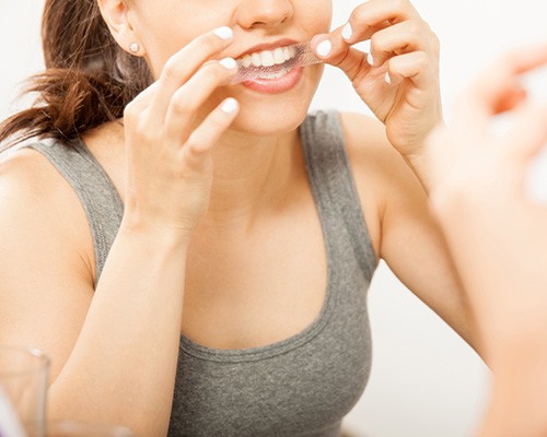 Woman putting on teeth whitening strip at home