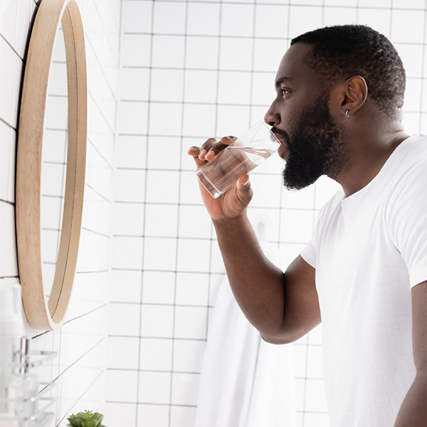 Man looking in bathroom mirror about to rinse with water