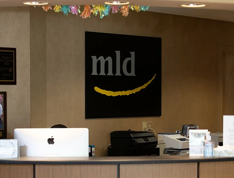 Front desk with Main Line Dental logo on wall