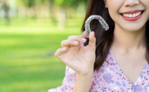 Woman holding clear aligner. 