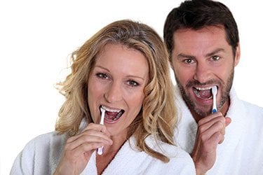 Photo showing a smiling woman and man, brushing their teeth in Wayne PA