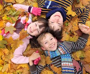 Photo showing smiling kids laying in leaves